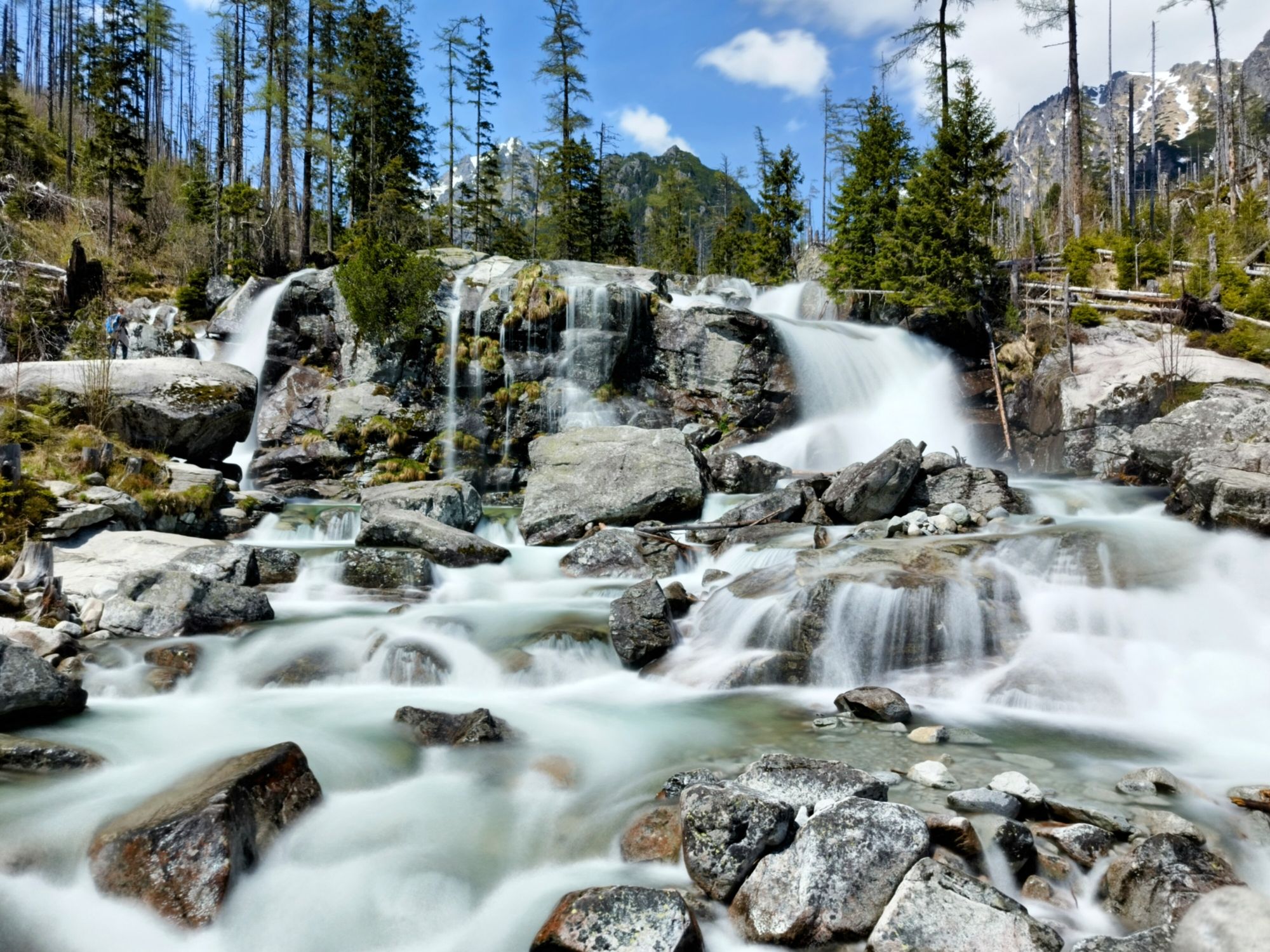Mountain scenery with human silhuete crosing river stream