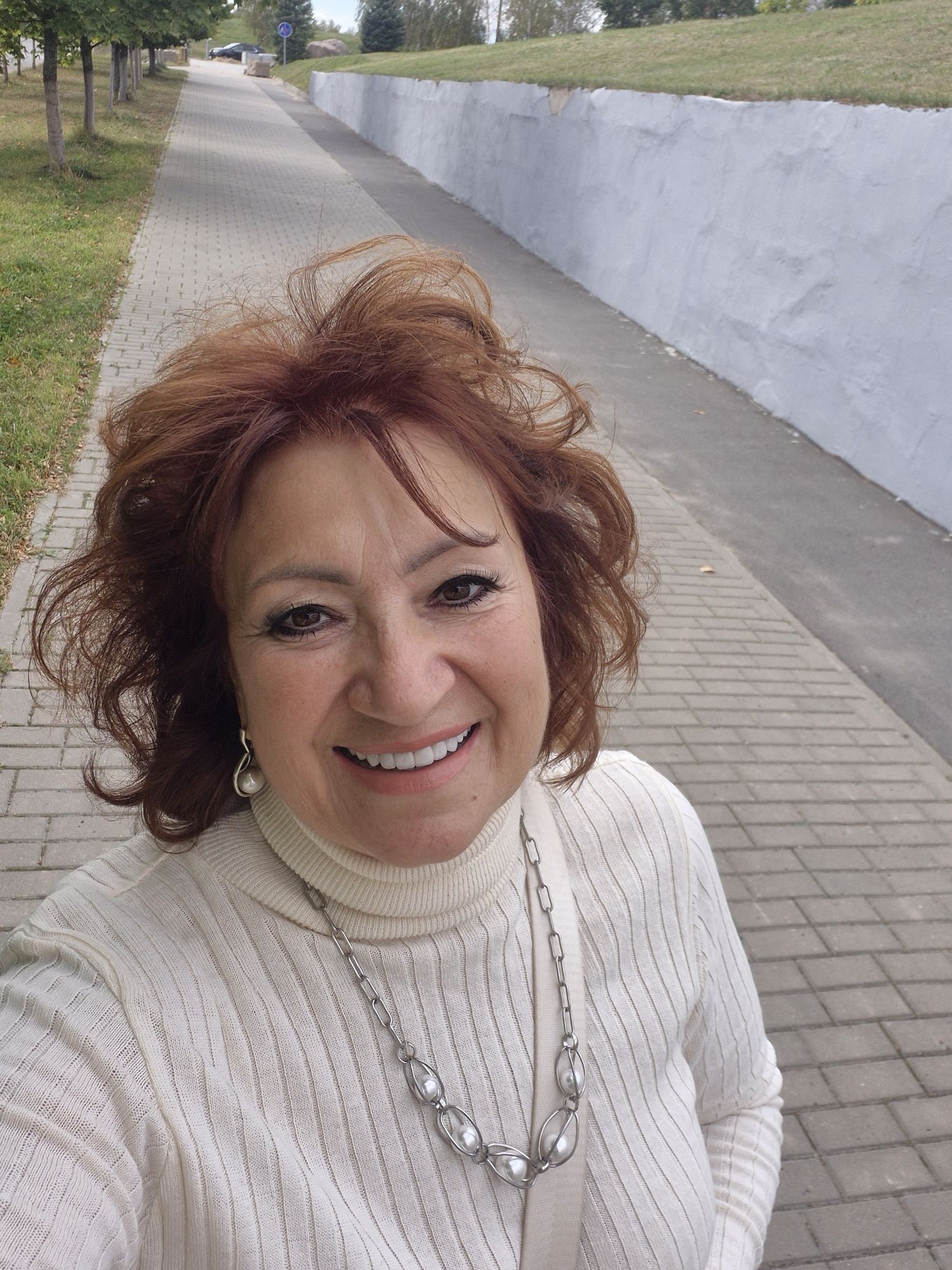 An elegant woman in a flowing, vintage-inspired gown, holding a single, perfect rose. She stands on a balcony overlooking a sprawling, art n...