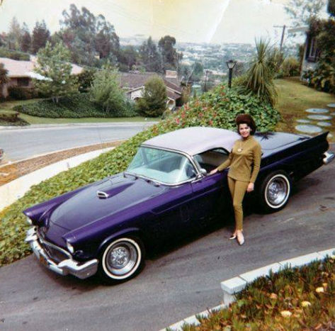 A fashionably attired businesswoman stands next to her Lincoln Continental parked on a steep hill in San Francisco, 1960s. 