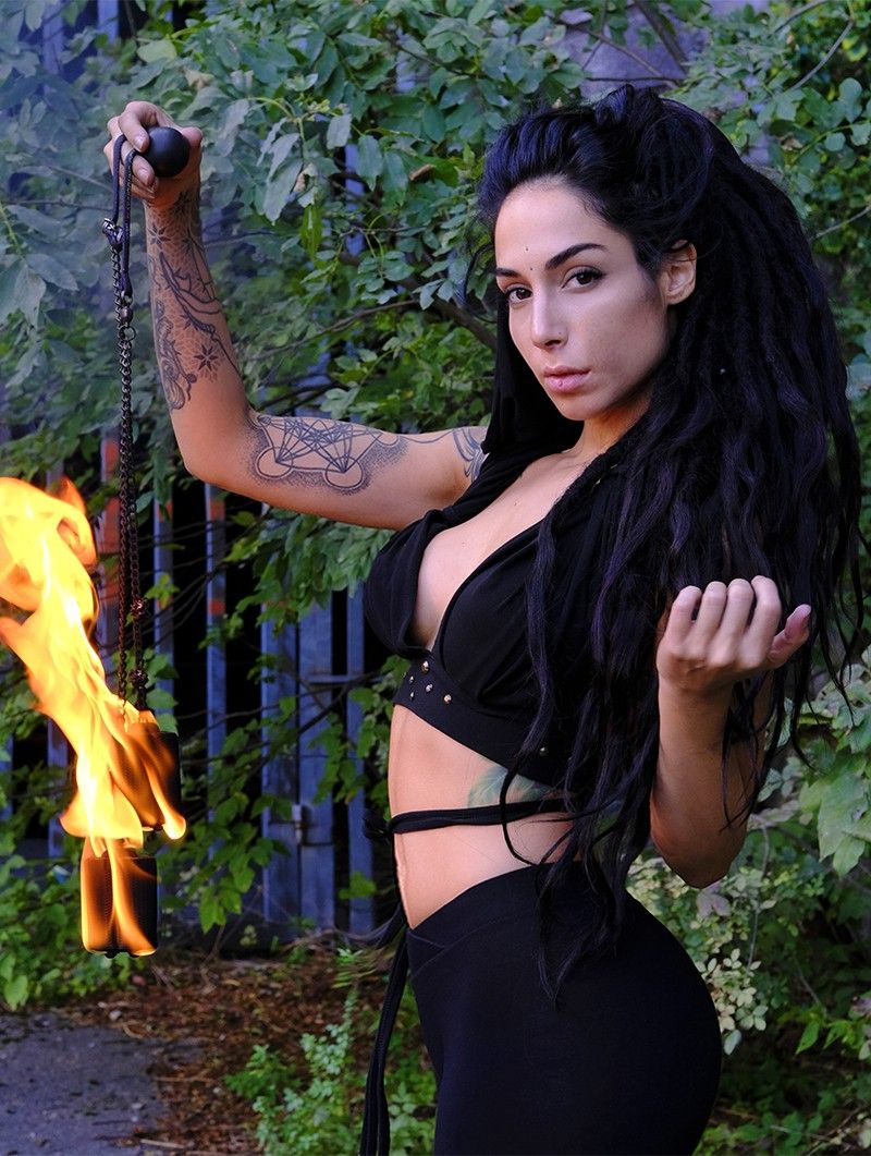 A captivating, cinematic portrait of a witch featuring a woman with cascading dark curly hair and an array of intricate tattoos. She dons si...