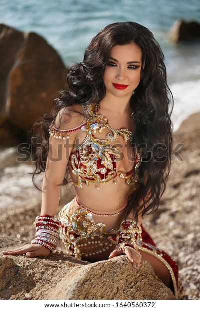 A captivating, cinematic portrait of a witch featuring a woman with cascading dark curly hair and an array of intricate tattoos. She dons si...