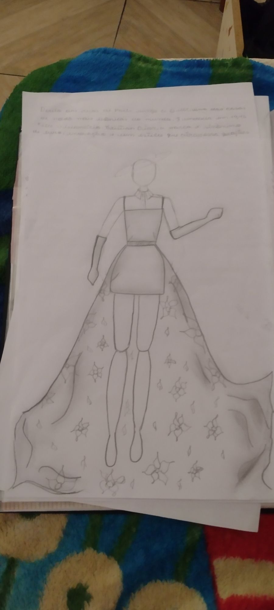 Vestido curto preto por cima de uma blusa social sem manga, luvas até o cotovelo e uma saia enorme de estampa floral na parte de trás 