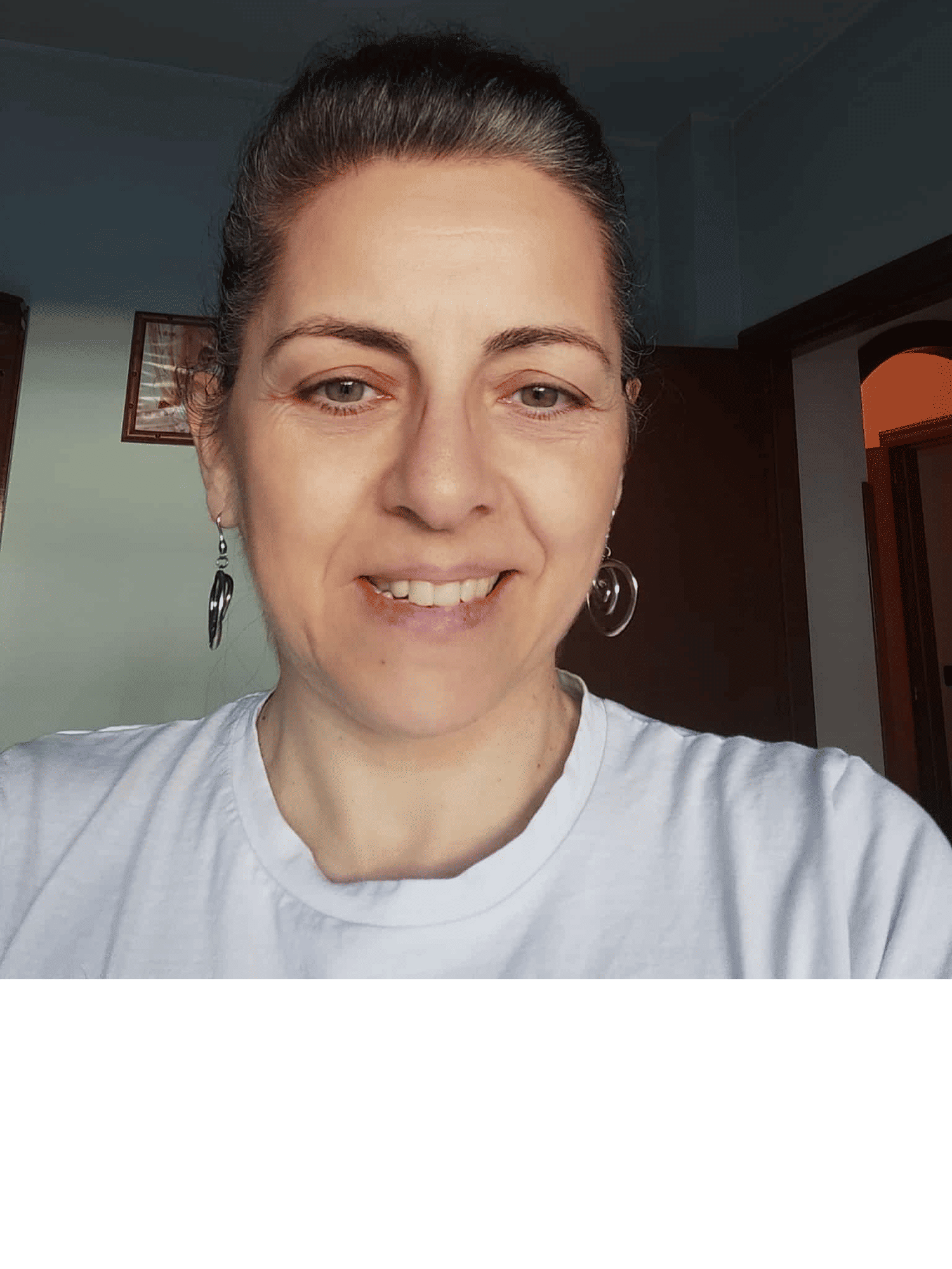 人物占画面的3/4，晴天景色，五官保持不变，头发改为黑色。修改服装和场景。上身穿浅皇家蓝圆领针织衫，颈部佩戴金色链条项链并悬一枚珍珠吊坠，耳佩细小金色耳环，整体清新优雅。皮肤逼真自然，略带噪点。照片为手机竖拍，为肩部以上特写。女子正面面对镜头，是一位意大利中年女性，眼神明亮灵动，...