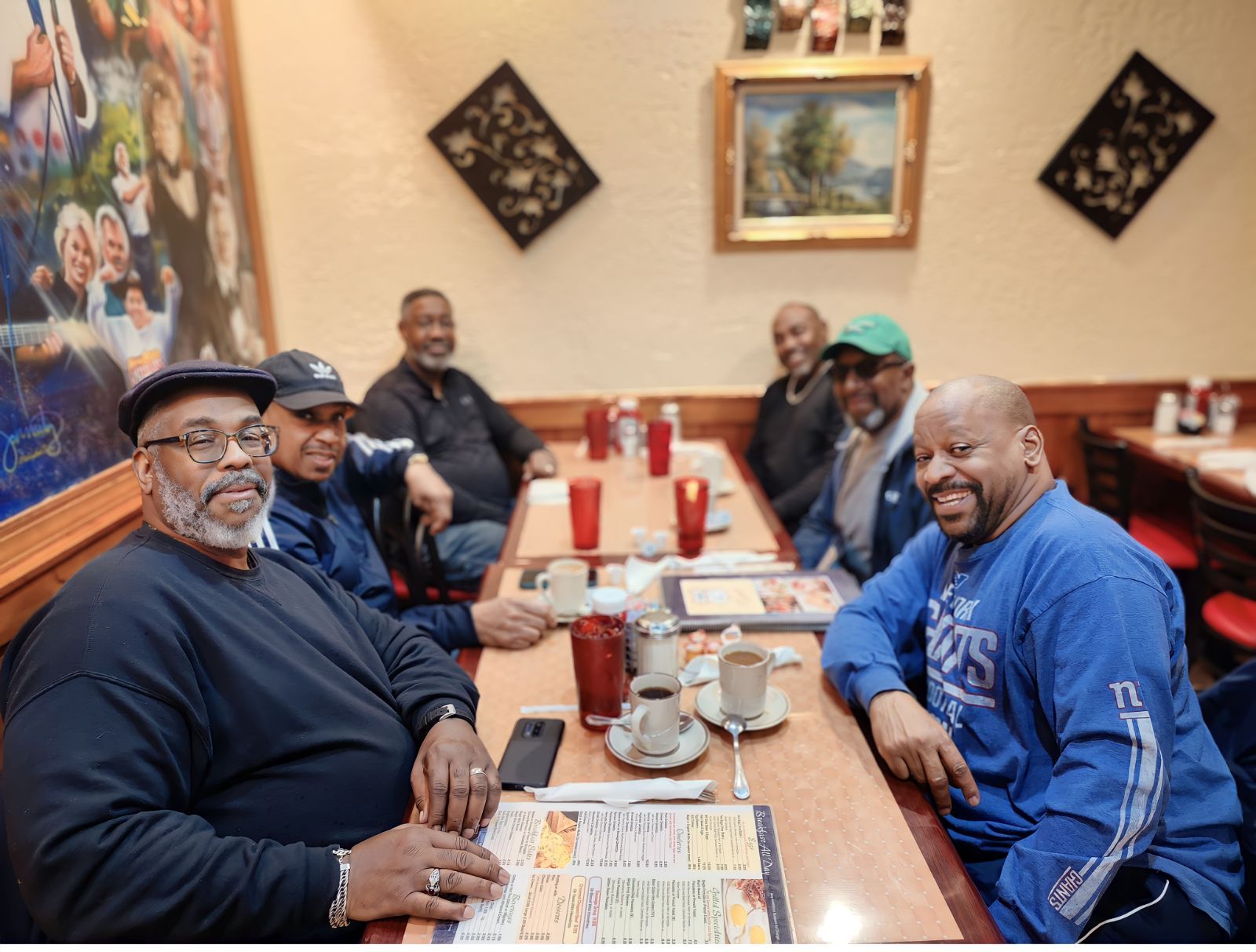 Photorealistic image of a group of 6 gorillas seated at a table having breakfast in a restaurant smiling at the camera