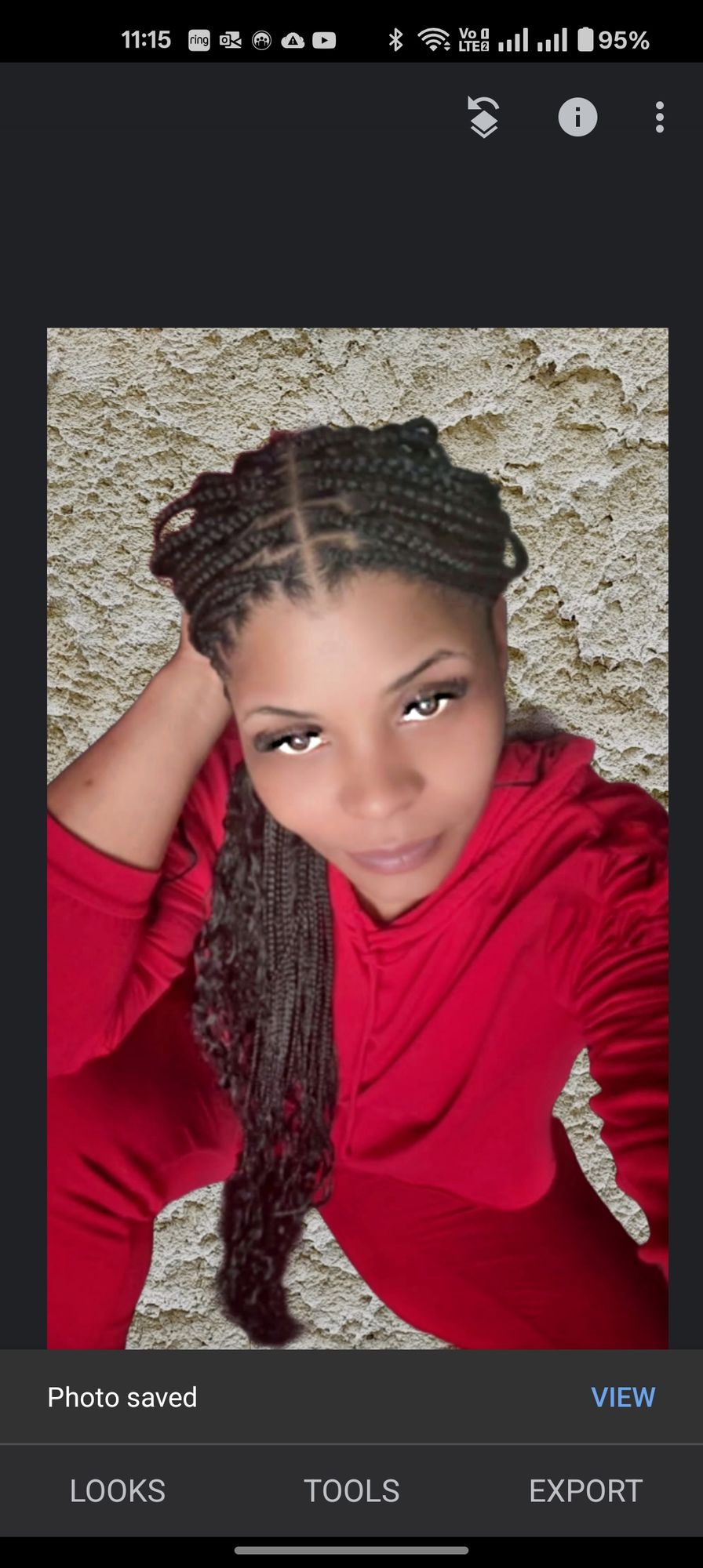 This image features a woman with braided hair, wearing a red hooded top and matching pants. She is looking directly at the viewer. Her right...