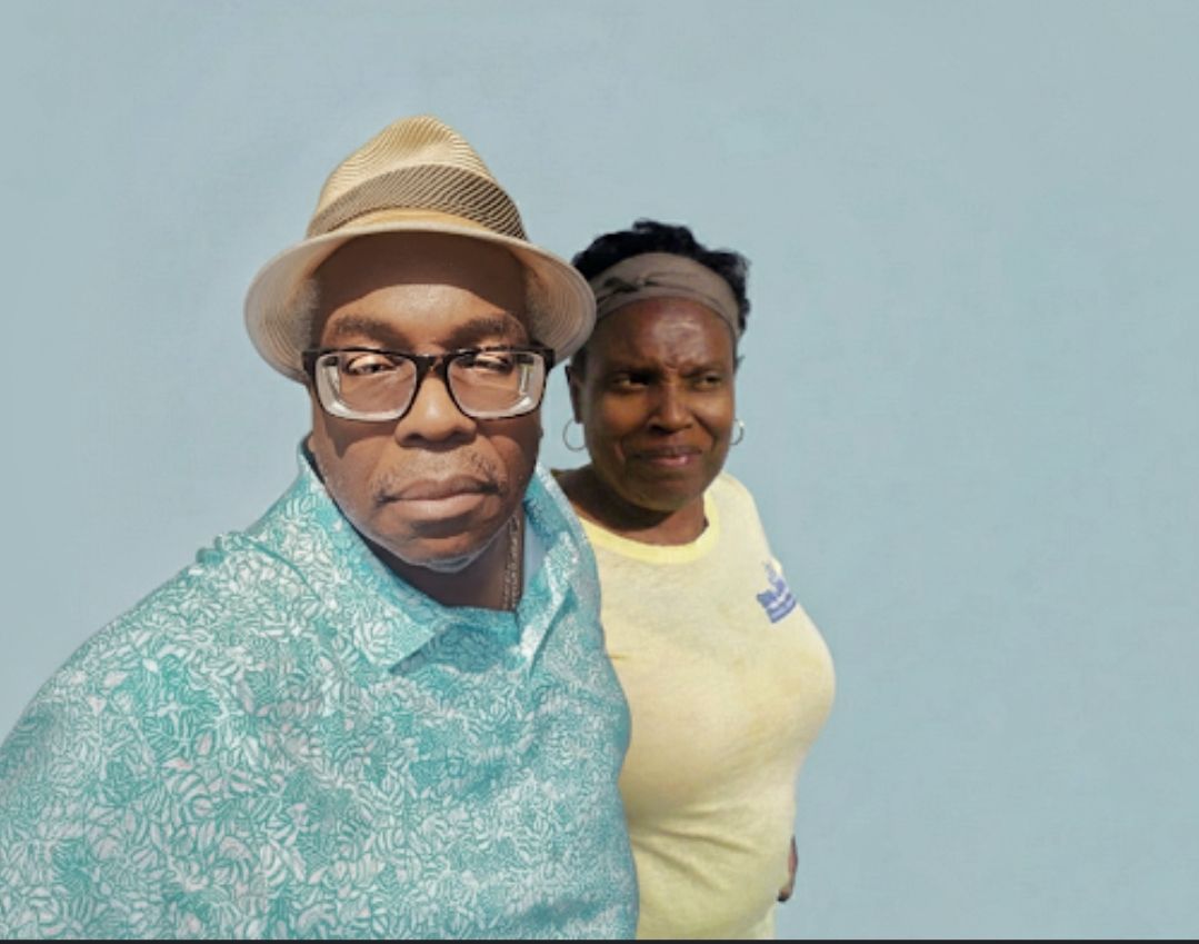 A photorealistic studio portrait of a Black couple. The man wears a light-colored fedora with a striped band, glasses, and a blue patterned ...