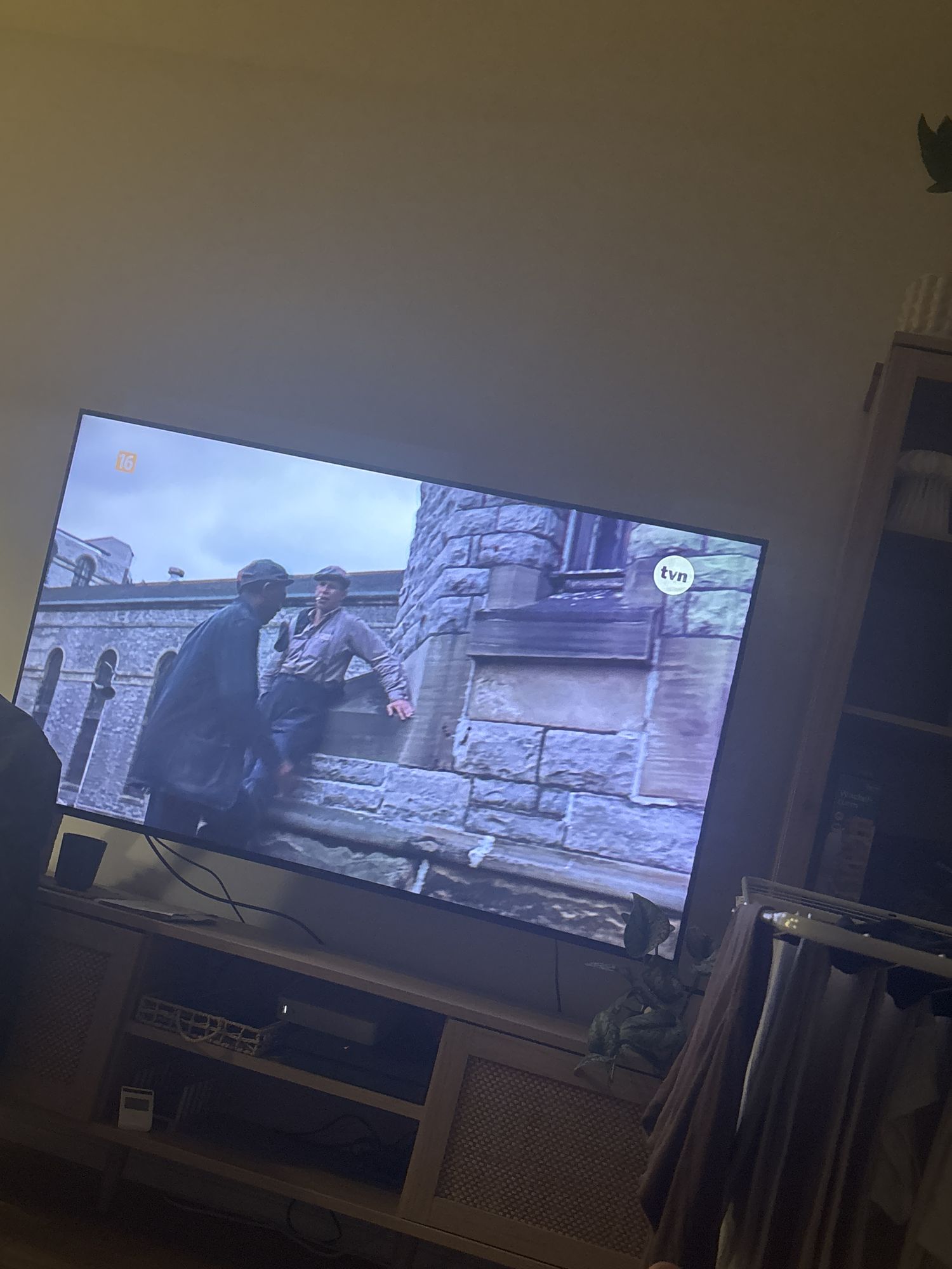 Czarny mężczyzna obraną się i wychodzi z ekranu telewizora i zaczyna tańczyć na głowie i klaska stopami 