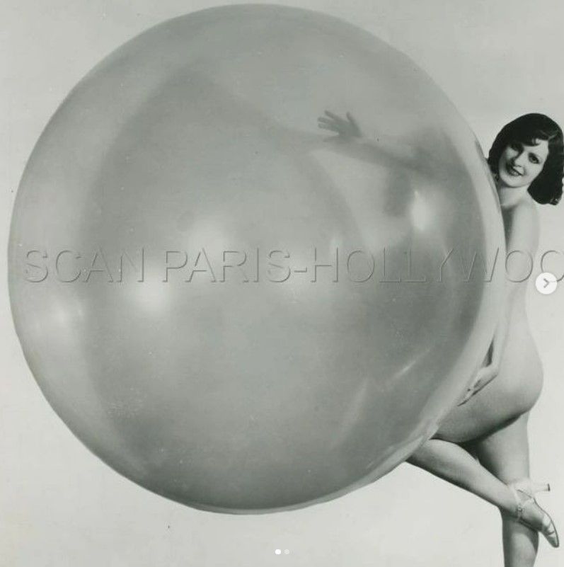 woman in a bikini holding an enormous white weather balloon.