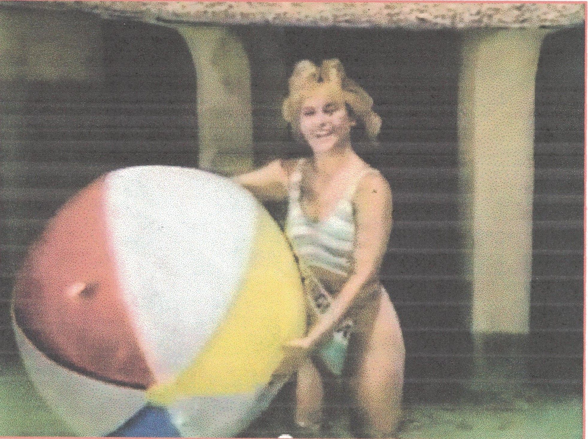 A beautiful Apache woman holding a big beach ball at the pool. 