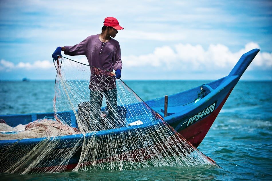 A grizzled fisherman, his face etched with years of sun and sea, mends his nets on a pier shrouded in thick, atmospheric fog. The only light...