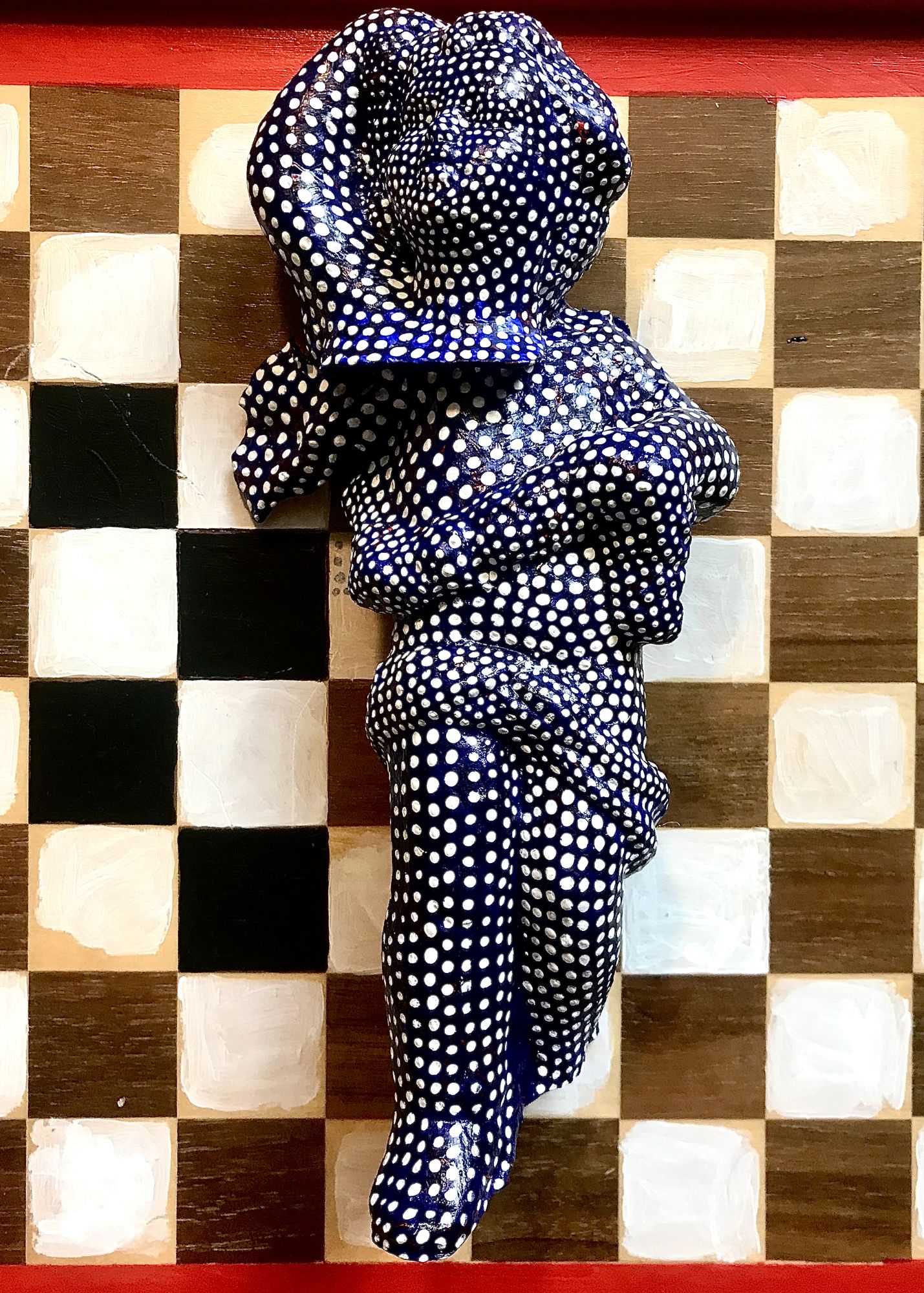 A cracked statuette of a boy angle covered in hypnotic dots on a background of a checkered chessboard dazzled by nein glow in this optic ill...