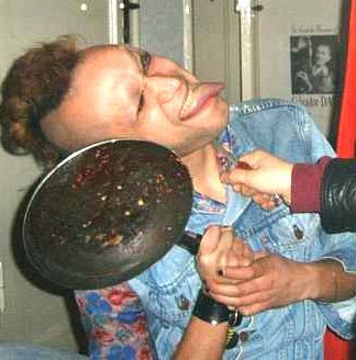 A monster alien with mohawk has its extremely long tongue out while it attacks its enemy with a frying-pan the enemy is outside the picture...