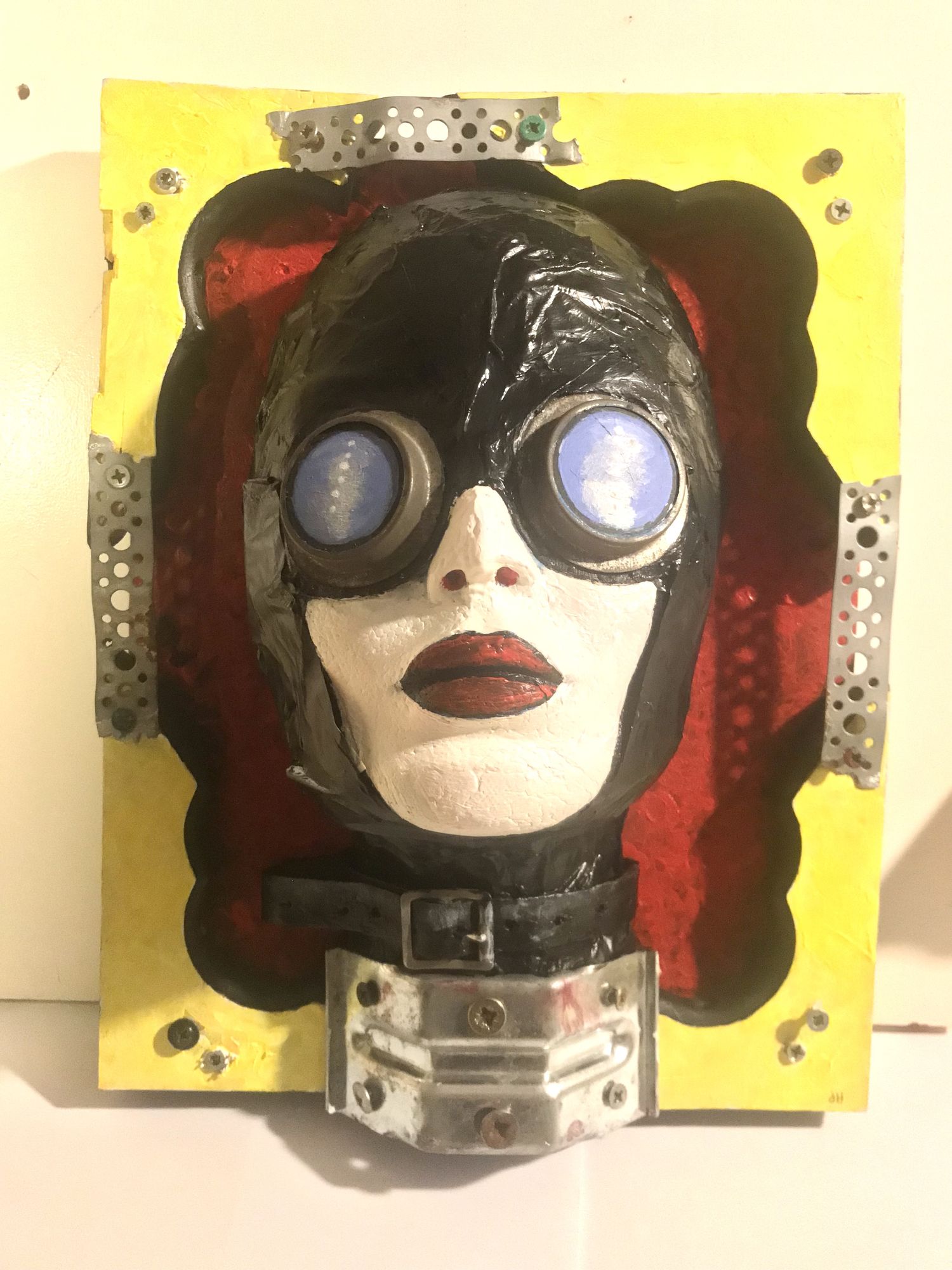 A frontal face of a black vinyl laced woman with goggles. A cross of styles like Rivet-head and steampunk sci-fi
