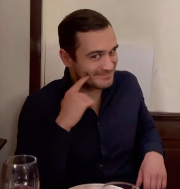 Leaning against a wall in a russian base with a pistol holstered on the pants  and the hand lightly touching the holster