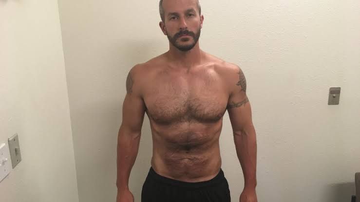 Chris watts (wearing an orange prison jumpsuit: 1.3) while (standing behind bars:1.7) 