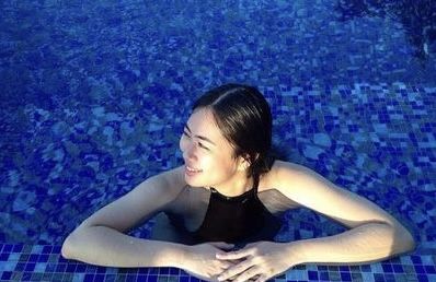 Pretty Asian girl in black swimsuit at swimming pool edge, photoshoot, face like model, slim, curvy