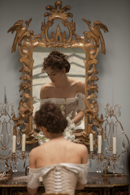 A beautiful medieval brunette young lady is sat on her dressing table, facing her mirrorand looking down. She wears a white medieval like dr...