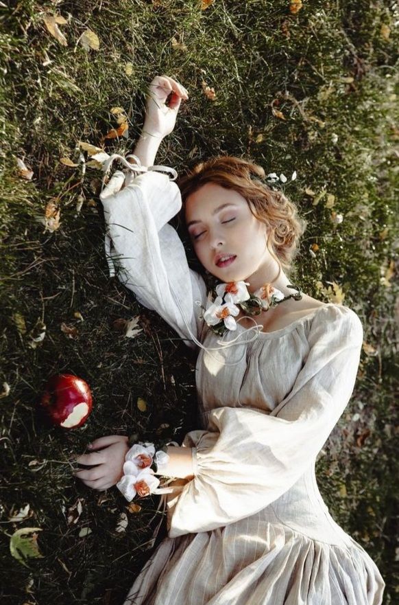 A young medieval brunette lady lays down, eyes closed, on the grass. Surrounded by autum leaves. Is she dead or asleep? She wear a silky nig...