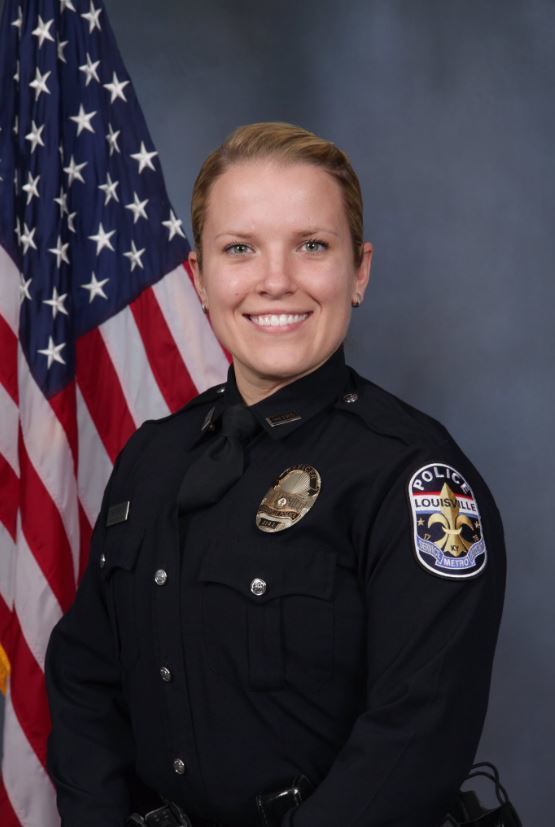 A young woman in a dark blue police uniform stands with variant face