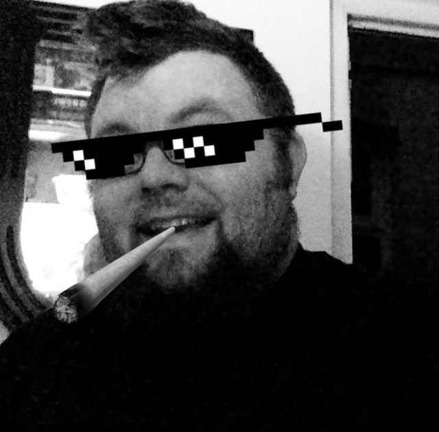 A friendly man smokes a massive blunt while wearing sunglasses