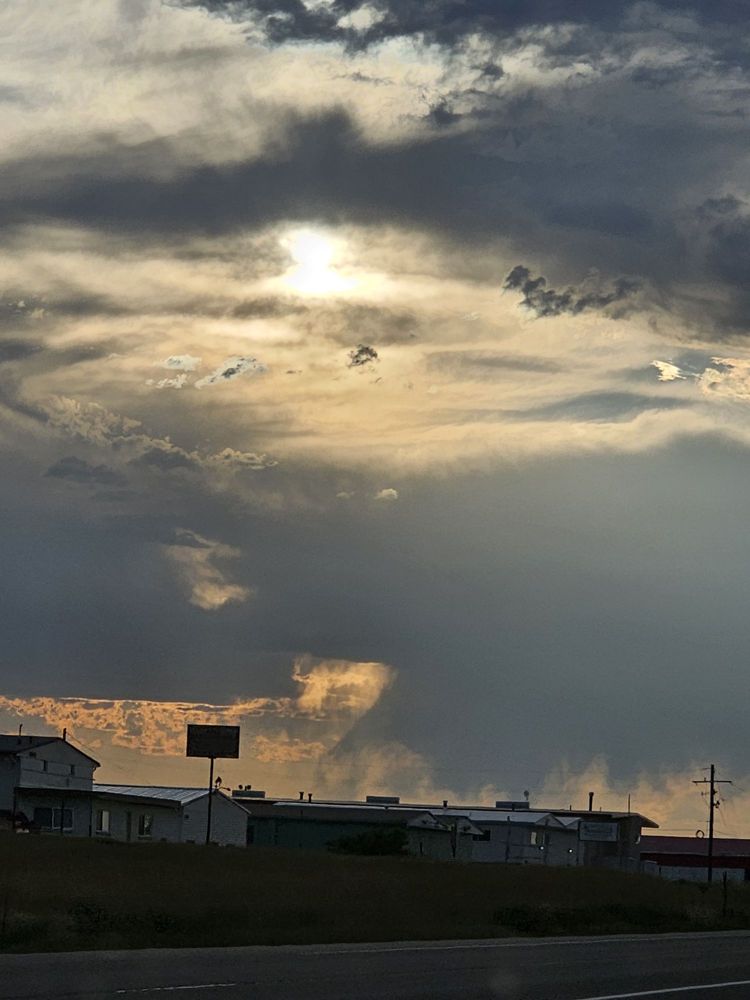 Medium shot. Long flowing black hair. Yellow eyes. Subtle smile. Sitting on a stone base looking up into the sky as it rains around her. A s...