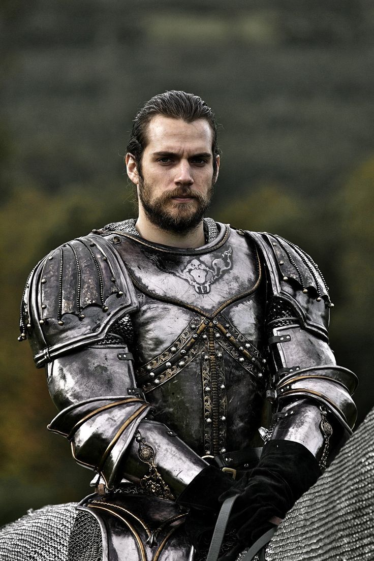 The series house of the dragon. A magnificent medieval field with a castle and horses running in the background. There is a handsome young l...